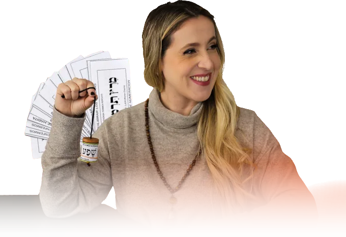 Darlene Abrileri sorrindo, segurando um Pêndulo Hebreu diante de cartões radiestésicos